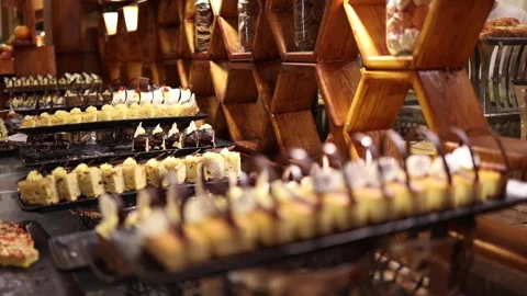Elegant dessert buffet lined with rows of colorful mini cakes topped with cream  Stock Footage 310808654