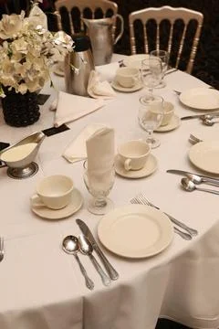 Elegant dining setting features white tableware and floral display for a fo.. Stock-Fotos