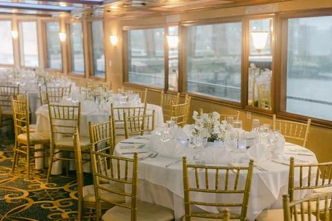 Elegant dining setup on a riverboat, showcasing floral centerpieces and fine Stock Photos