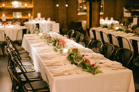 Elegant dining setup with white tablecloths and floral centerpieces in a cozy Stock-Fotos