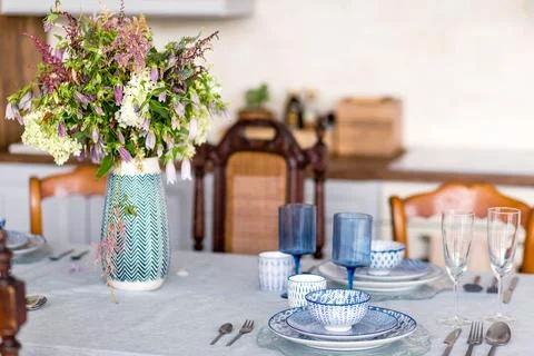 Elegant dining table set with blue and white porcelain dishes, glassware, and a Stock Photos
