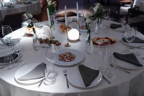 Elegant dining table set with fine dishes, glasses, and floral centerpieces Stock Photos