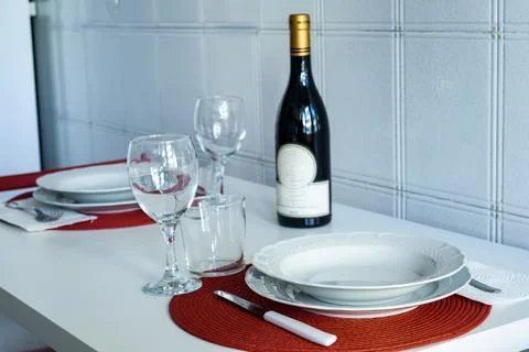 Elegant dining table set for two with wine bottle and red placemats Stock Photos