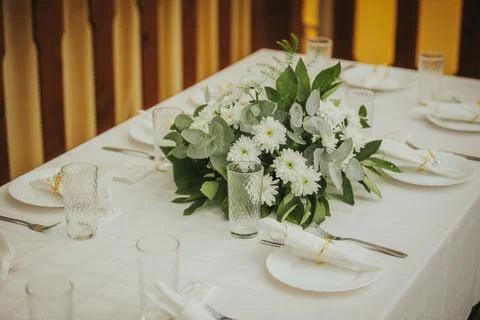 Elegant dining table set with white plates, glassware, and a floral centerp.. Stock Photos