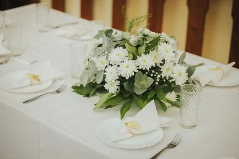 Elegant dining table set with white tablecloth, floral centerpiece of white.. Stock Photos