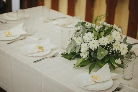 Elegant dining table set with white tablecloth, floral centerpiece of white.. Stock Photos