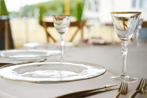 Elegant dining table setting with clear glass plates, crystal wine glasses, and Stock Photos