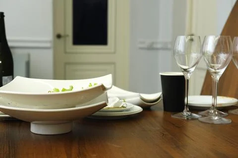 Elegant dining table setting featuring white ceramic bowls, wine glasses, and a Фото