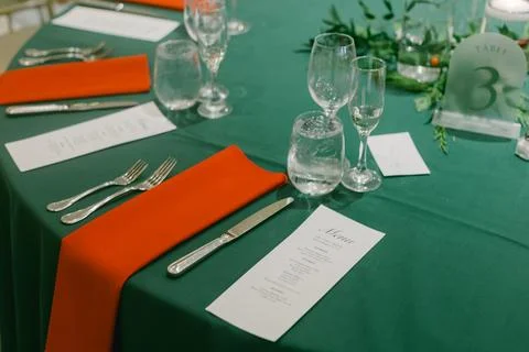 Elegant dining table setting with green tablecloth and orange napkins arranged 스톡 사진