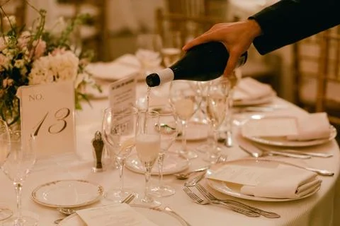 Elegant dinner setting features a waiter pouring champagne at a sophisticated Stock Photos