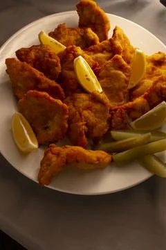 Elegant dinner setting featuring crispy fried chicken and lemon wedges Stock-Fotos