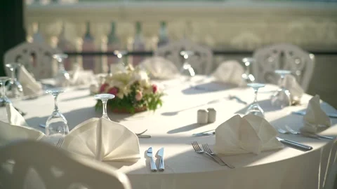 Elegant dinner table stands prepared before sunset with plates - Luxury Service Stock Footage 339737281