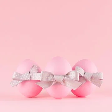 Elegant easter eggs with silver bow standing on pastel pink background, squar Stock Photos