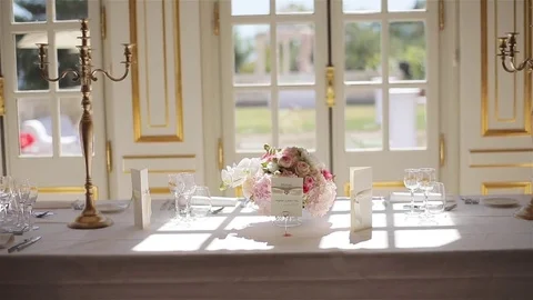 Elegant festive table set with glasses and flowers bouquet at sun light close up Stock Footage 79969641