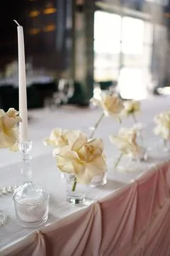 Elegant festive table setting with white roses, candles and delicate fabric d Stock Photos