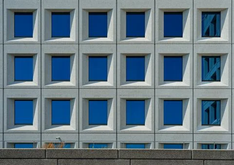 Elegant Granite Facade with Multiple Windows Reflecting Blue Sky Stock Photos