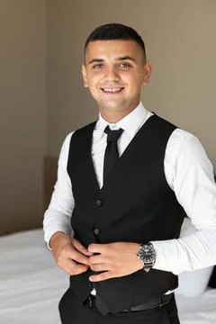 Elegant Groom Getting Ready, Buttoning Waistcoat in Hotel Room Stock Photos