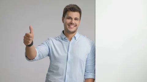 Elegant guy leaning against wall and making thumb up gesture Vidéo 77790113