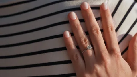 An Elegant Hand Displaying a Ring Resting on Beautifully Striped Fabric Material Stock Footage 314576523