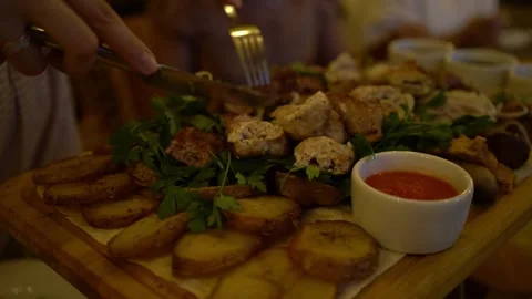 Elegant hands slice tender grilled kebab on platter with greens Video stock 342193623