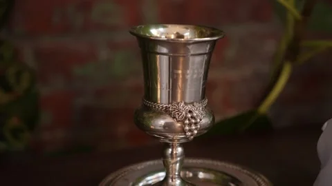 Elegant Kiddush Cup With Candle Reflections, Ceremonial Silver Wine Cup Amid Video stock 323780371