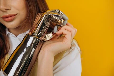 Elegant lady holds bionic prosthesis with hand on yellow Stock Photos