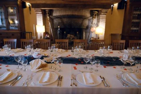 Elegant long dining table set for a formal event with rose petals and a fir.. Stock Photos