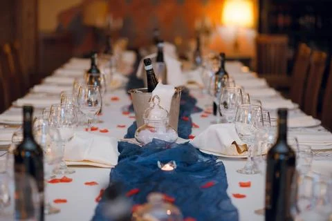 Elegant long dining table set for a romantic celebration with wine and rose.. Stock Photos