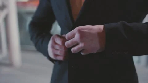 An Elegant Man Dressed in a Suit Adjusting His Attire Thoughtfully Under the Stock Footage 304265038