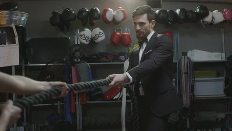 Elegant man pulls rope in competition with wife Stock Footage 106935384