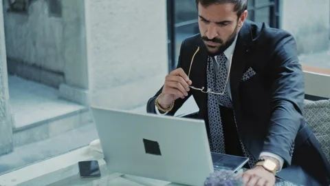 Elegant man taking off sunglasses while working on laptop Stock Footage 96297449