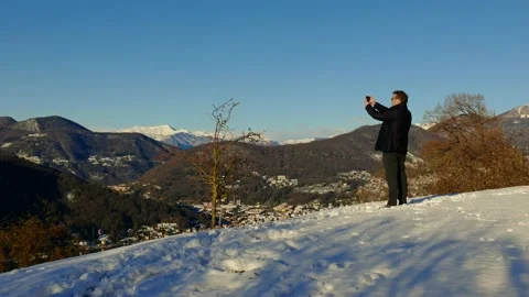 Elegant Man Using Smartphone and Making Photos and Joy Mountain View with Snow 库存影片 194011775