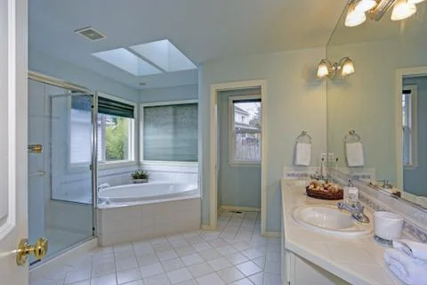 Elegant master bathroom features soft blue walls paint color, twin skylights  Stock Photos