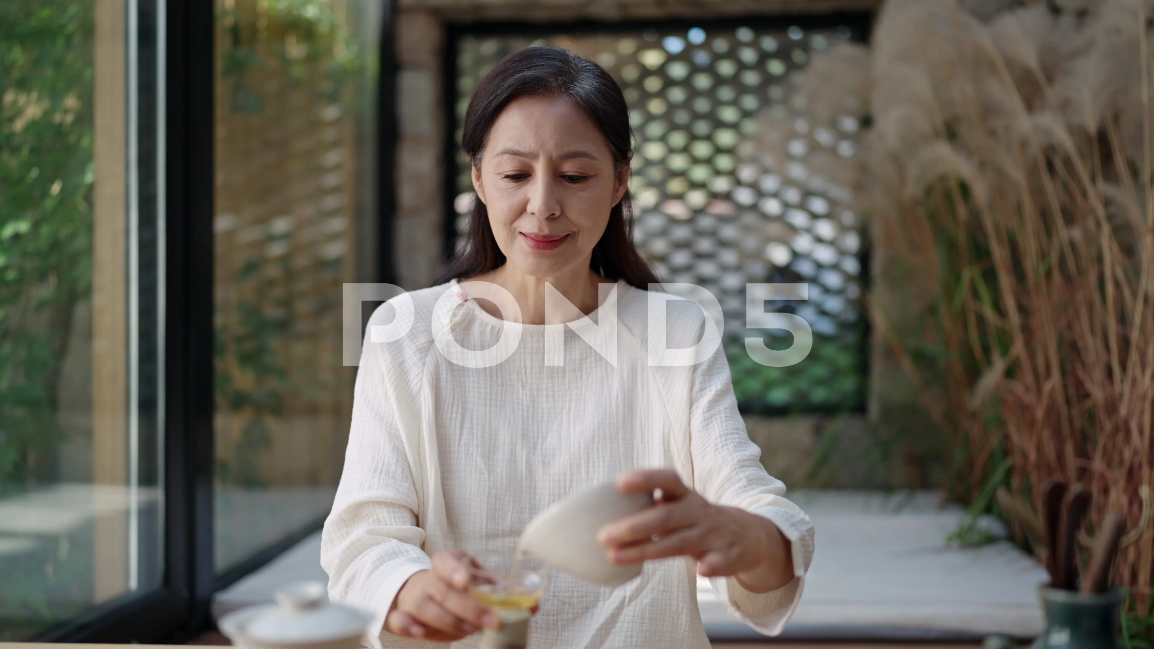 Elegant mature Chinese woman drinking tea in tea room,4K