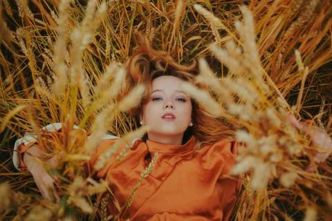 An elegant model lies on a wheat field enjoys nature. The concept of natural  Stock Photos
