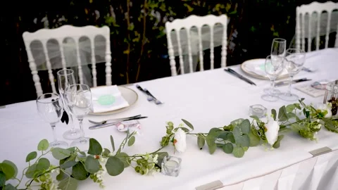 Elegant outdoor dining setup with lush greenery and delicate tableware in a Stock Footage 323911244