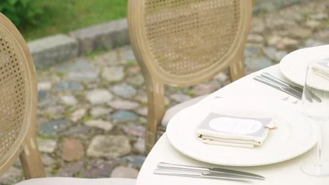 Elegant Outdoor Table Setting on Cobblestone Patio with Vintage Chairs Stock Footage 338166390