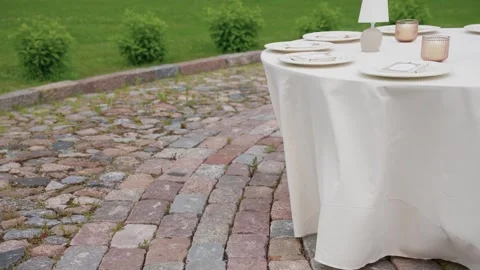 Elegant Outdoor Table Setting on Cobblestone Patio with Modern Decor Stock Footage 338166396