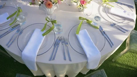 Elegant Outdoor Table Setting with Floral Centerpieces and Sunlit White Linens Stock Footage 345235084