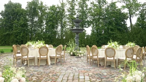 Elegant Outdoor Wedding Reception Setup with Fountain and Floral Centerpieces Stock Footage 338126546