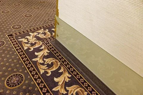 Elegant patterned carpet and textured wall with decorative baseboard in int.. Stock Photos