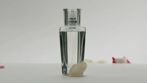 Elegant Perfume Bottle with Delicate Rose Petals on White Background Stock-Footage 312455204