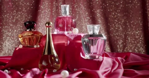 Elegant Perfume Bottles Display on Red Fabric with Glitter Background Vidéo 342805096