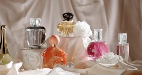 Elegant Perfume Bottles Displayed with Decorative Flowers on Satin Fabric Stock-Footage 313050901