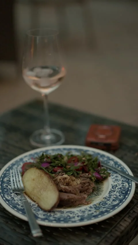 Elegant plated dinner with roasted meat, potato, fresh salad, and wine glass on Stock Footage 345267544