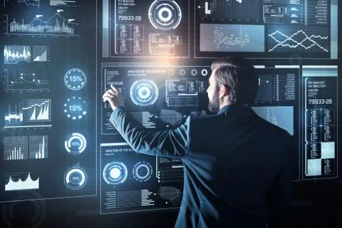 Elegant programmer standing in front of a futuristic device and touching it 库存照片