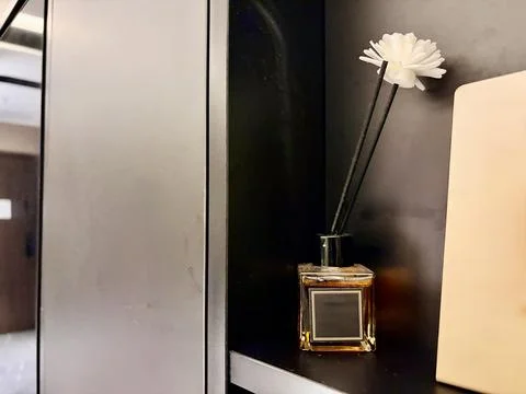 Elegant Reed Diffuser with White Flower on Black Shelf Foto stock