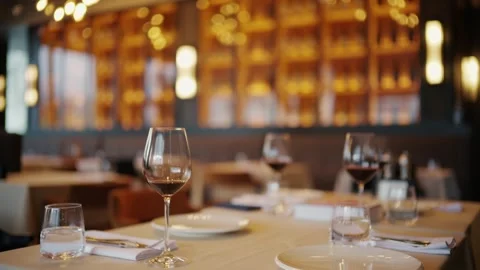 Elegant restaurant dining table setting with wine glasses and ambient light.. Stockbeeldmateriaal 339755363