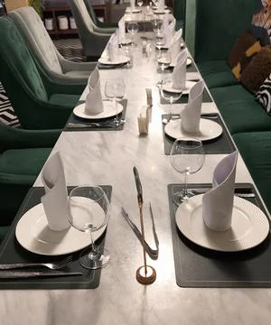 Elegant restaurant interior with table setting and green velvet chairs Stock Photos
