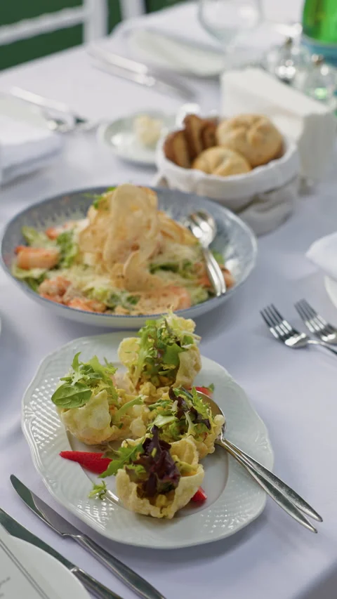 Elegant restaurant table set with fresh plated salad, bread basket, polished Stock Footage 337648267